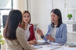 © amnaj - Three businesswomen having a meeting in a modern office, discussing important matters with determination and collaboration.