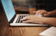 © Lyndon/peopleimages.com - Hands, typing and laptop on table for idea, planning and online research or communication. Person, technology and fingers on keyboard for remote working, studying or internet news and social media