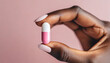 © Your Hand Please - woman's hand delicately pinching pink and white birth control pill, symbolizing autonomy in healthcare choices