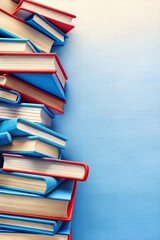 Wall Mural - Neatly stacked pile of colorful books on a blue background with ample space for text, perfect for educational themes