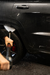 Wall Mural - Using high pressure streams of water to ensure a deep and effective clean of the vehicle's surfaces. Cleaning car on the self service car washer. Wheel washing.