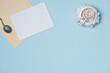 © Solesto - Envelope with empty white paper list and women's jewelry in vintage style on blue background from above. Copy space