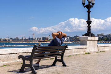 Wall Mural - Man resting on a bench at Emperor Augustus seafront (Lungomare Imperatore Augusto), promenade by Adriatic Sea, Bari, Italy, Apulia