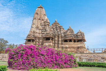 Ancient Indian Khajuraho temple of structure featuring intricate carvings and vibrant floral foreground