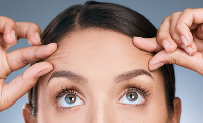 Sticker - Close up, woman and hands on forehead in studio for skin care, wellness and thinking of facial. Eyes, filler and idea for dermatology by blue background with cosmetics and collagen for detox