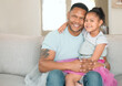 © peopleimages.com - Family, portrait and happy for love, relax and trust in home living room with couch, dad and child. Father, girl and smile as household for bond or support together in house lounge on sofa with skirt