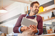 © Arnell Koegelenberg/peopleimages.com - Coffee shop, small business and man on tablet for online menu, checking stock and order inventory. Restaurant, cafeteria and happy owner on digital tech for social media, networking and website