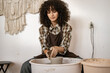 © sofiko14 - Young adult woman working on ceramic dish on potter's wheel. Focused on craft creation with relaxed ambiance in pottery studio.