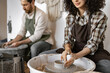 © sofiko14 - Man and woman working together creating pottery using clay on potter's wheel in a studio.