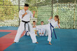 © New Africa - Girl practicing karate with coach on tatami outdoors