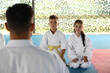 © New Africa - Children and coach sitting on tatami outdoors. Karate practice