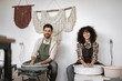 © sofiko14 - Man and woman potters at work with potter's wheel creating clay vase in artistic studio setting.