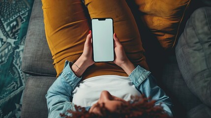 Woman using phone. Top view of young woman lying on sofa holding smartphone with blank screen. Template for interface, chat, web app, online advertising, mobile game, social network.