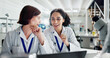 © peopleimages.com - Women, celebration and laptop in lab for science, notification or approval for research project. People, scientist and lab partner with computer for cheers, excited or results for funding application