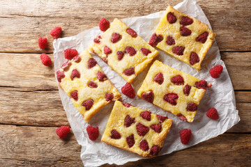 Wall Mural - Sweet custard pie tart with fresh berry raspberries closeup on the paper on the wooden table. Horizontal top view from above