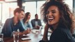 © nopommajun - A woman with curly hair laughs exuberantly in a social setting with friends blurred in the background at a restaurant