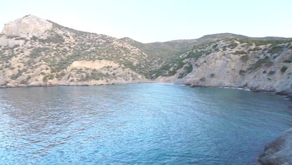 Wall Mural - A rocky shoreline with a small body of water in the foreground. The water is calm and clear, and the shoreline is lined with trees. The scene is peaceful and serene, with the water.