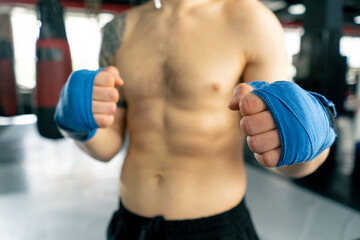 Wall Mural - close-up in boxing fight club, a bald young boxer with tattoos in blue bandages stretches his hands before a fight professional training