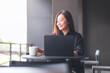 © Farknot Architect - Portrait image of a young woman drinking coffee while working on laptop computer in cafe