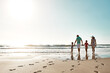 © peopleimages.com - Happy family, walking and holding hands at beach in summer for relax, travel and holiday in Miami. Parents, children and people at ocean with back for vacation, bonding and trust together by water