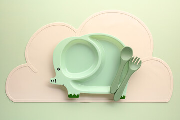 Creative kids dining set designed as a cute elephant and silicone cutlery on a green background.