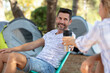 © auremar - cheerful couple on camping holiday passing a hot drink
