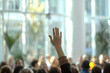 © AspctStyle - Raised hand in a large crowd, seeking attention or participation, bright and airy indoor setting with blurred people in the background