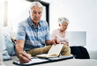 © ReadyAtTheEase/peopleimages.com - Senior couple, laptop and serious with writing on document in sofa for retirement or shopping list for household. People, planning and budgeting at home for savings, insurance and asset management
