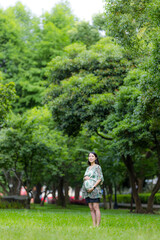 Wall Mural - Pregnant woman with the green park background