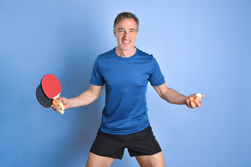 Wall Mural - Smiling man in sportswear with ping-pong equipment blue isolated background