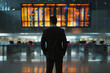 © lashkhidzetim - A man in a suit is looking at a large display of flight information. The man is focused and attentive, possibly waiting for his flight or checking for updates