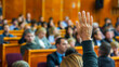 © volga - Adult attention in a conference hall raising hand to ask a question
