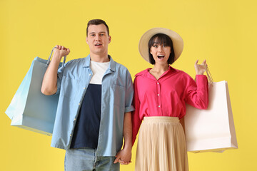 Wall Mural - Young couple in love with shopping bags on yellow background