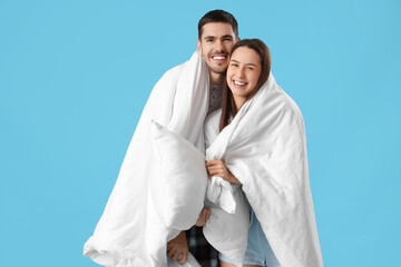 Wall Mural - Young couple with blanket and pillows on blue background