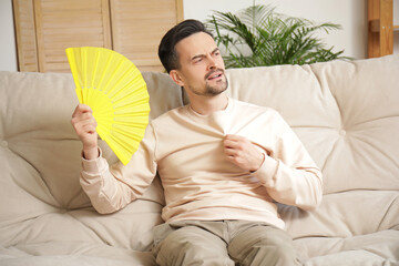 Sticker - Young man with fan on sofa at home