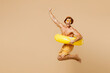 © ViDi Studio - Full body young man wears yellow shorts swimsuit hat relax rest near hotel pool jump in inflatable ring do winner gesture isolated on plain beige background. Summer hot vacation sea sun tan concept.