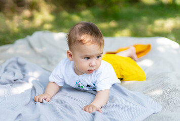 Sticker - A baby is laying on a blanket in the grass. The baby is wearing a yellow skirt and a white shirt