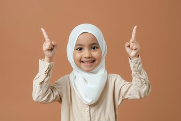 Angry Asian Muslim little girl points to empty space for text or ads