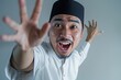 © typepng - The happy young Asian Muslim man with his hand waving is isolated on a white background for a concept of Ramadan and Eid Mubarak.