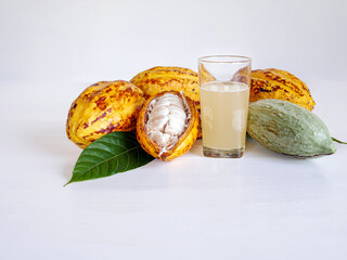 Wall Mural - Fresh cacao water in glass and half sliced ripe yellow cacao pod with white cocoa seed, Cacao juice in glass  on white wooden background