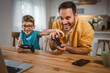 © Miljan Živković - Father and son play video games on laptop with joystick at home