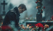 © anatoliycherkas - Christian man crying next to a grave with a headstone for a deceased relative in the family