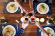 © peopleimages.com - Food, hands and wine toast by friends in house for top view birthday celebration, congratulations or reunion event. Glass, cheers or people in solidarity for brunch, meal or drinks at dinner party