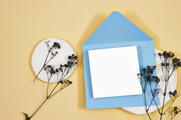 Wall Mural - blue envelope with Blank paper and black gypsophila flowers above marble podium - White paper sheet on beige background