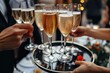 © Lens Legacy - Festive shot of hands taking glasses of champagne from a silver tray, capturing the lively spirit of the event