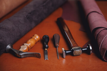 Banner tailor industry craftsman. Leather rolls of natural color and tools for handmade craft in workshop