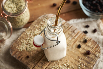 Wall Mural - Vegan hemp seed milk in a glass bottle with an ecological stainless steel straw