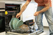 © Lucia PSV - young man putting a dishwasher in his house after a meal. Man doing housework.