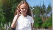 © Mariia - Positive pretty little girl going road on park in the white t-shirt and jeans shorts sunny weather warm season.