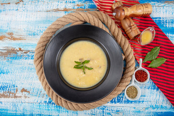 Wall Mural - Fish soup in a bowl. Fish soup with cream, sauces, lemon, herbs and croutons on wooden background.